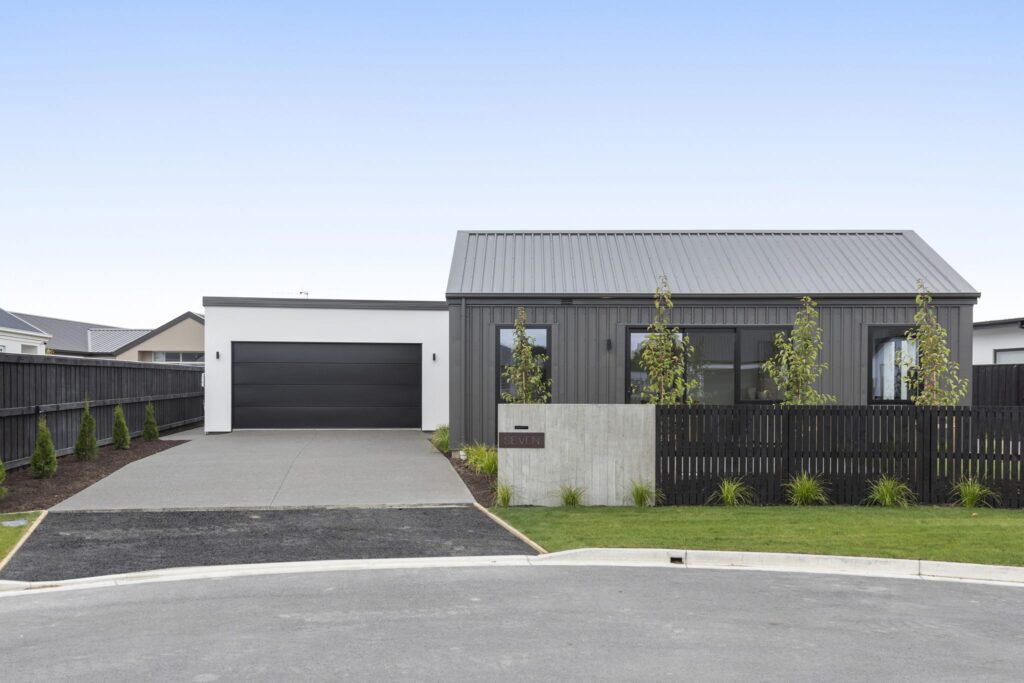 Front exterior of a modern new build house featuring clean architectural lines and landscaped grounds, ideal for homes for sale.
