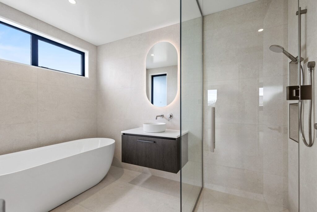Modern bathroom interior in a new build home at Woodleigh Lane, featuring a freestanding bath, tiled walk in shower and contemporary vanity, showcasing modern house design in architectural homes for sale.