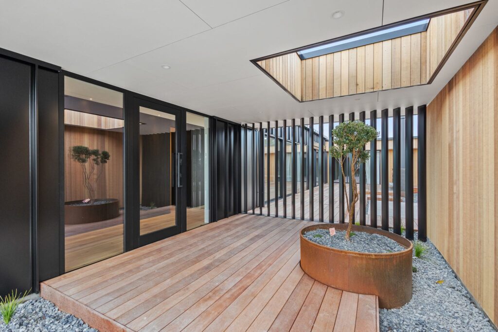 Covered courtyard with timber decking in an architectural home, highlighting modern house design and luxury living.